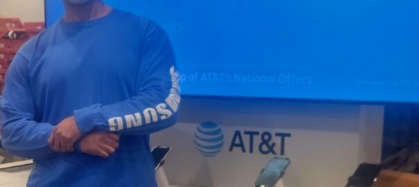 Curtis Matthews standing in front of an AT&T display, representing his professional role as an AT&T business consultant and highlighting his personal story connected to his name.